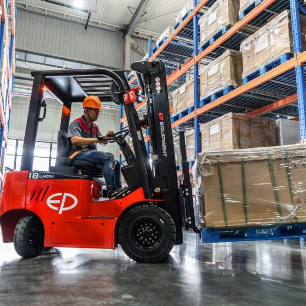 Tài xế vận hành xe nâng điện ngồi lái EP EFL 183 1.8 tấn trong kho, trải nghiệm sự êm ái nhờ bơm bánh răng độ ồn thấp và trục lái giảm xóc.