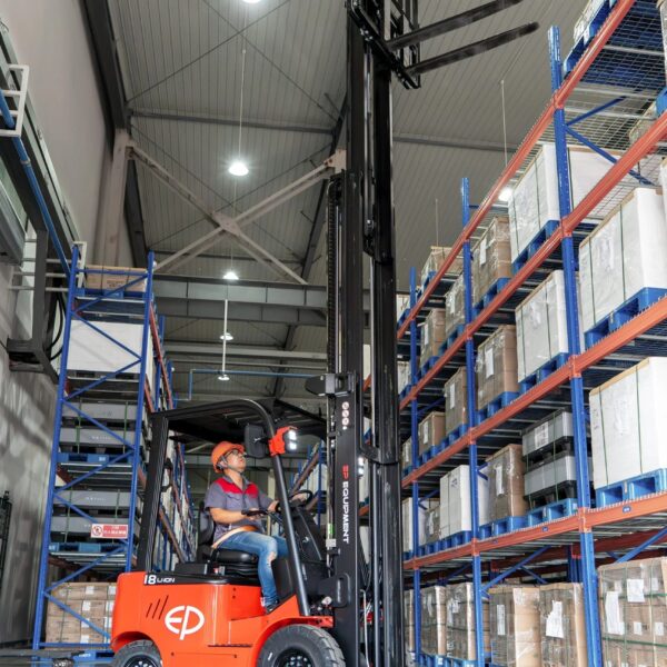 Tài xế vận hành xe nâng điện ngồi lái EP EFL 183 1.8 tấn trong kho, trải nghiệm sự êm ái nhờ bơm bánh răng độ ồn thấp và trục lái giảm xóc.
