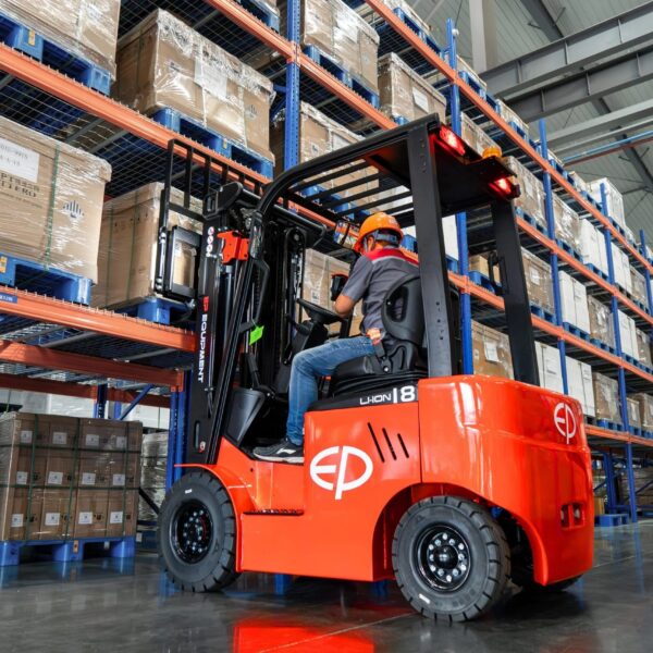 Tài xế vận hành xe nâng điện ngồi lái EP EFL 183 1.8 tấn trong kho, trải nghiệm sự êm ái nhờ bơm bánh răng độ ồn thấp và trục lái giảm xóc.